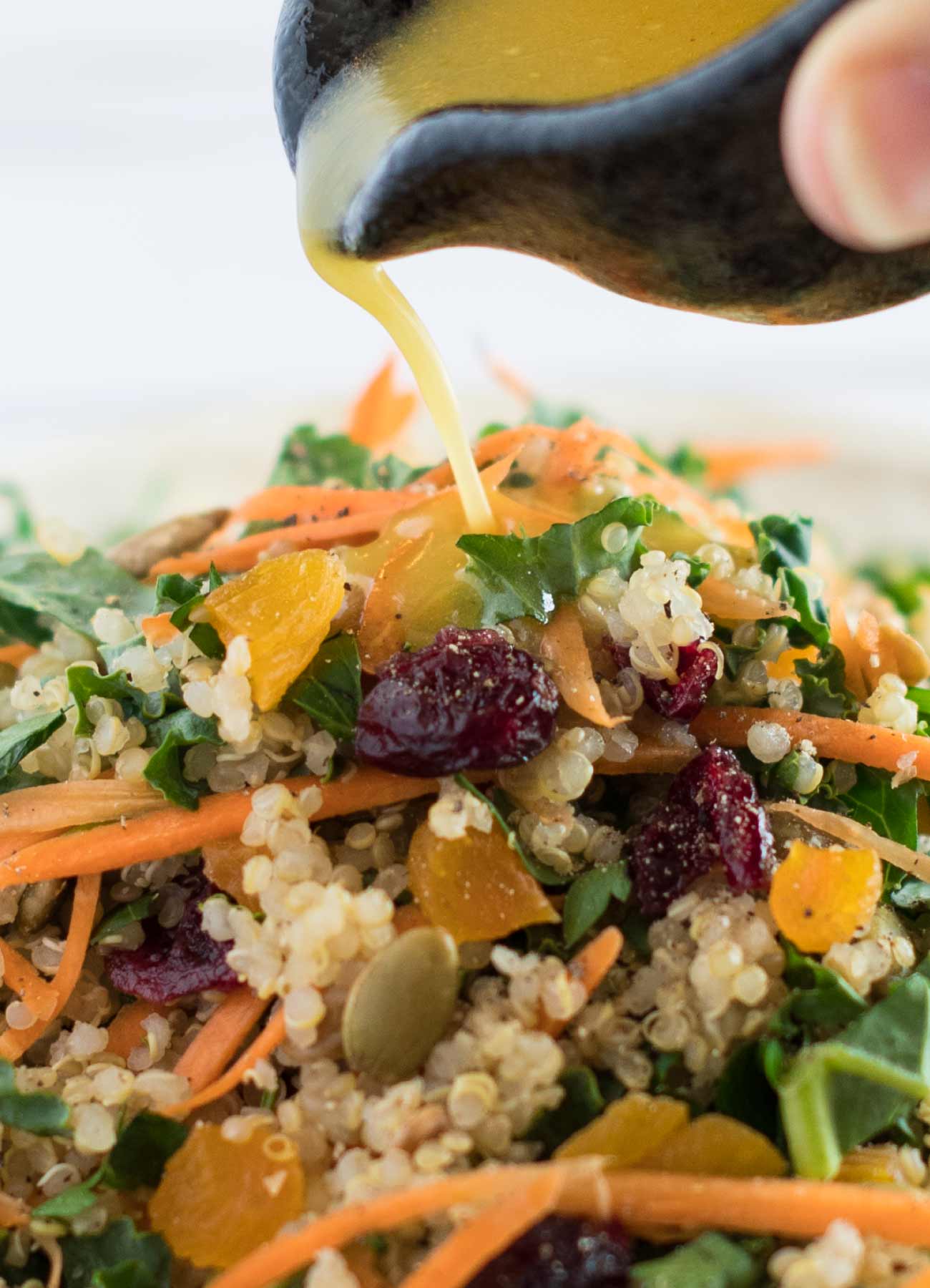 Citrus maple dressing pouring over kale and quinoa salad.