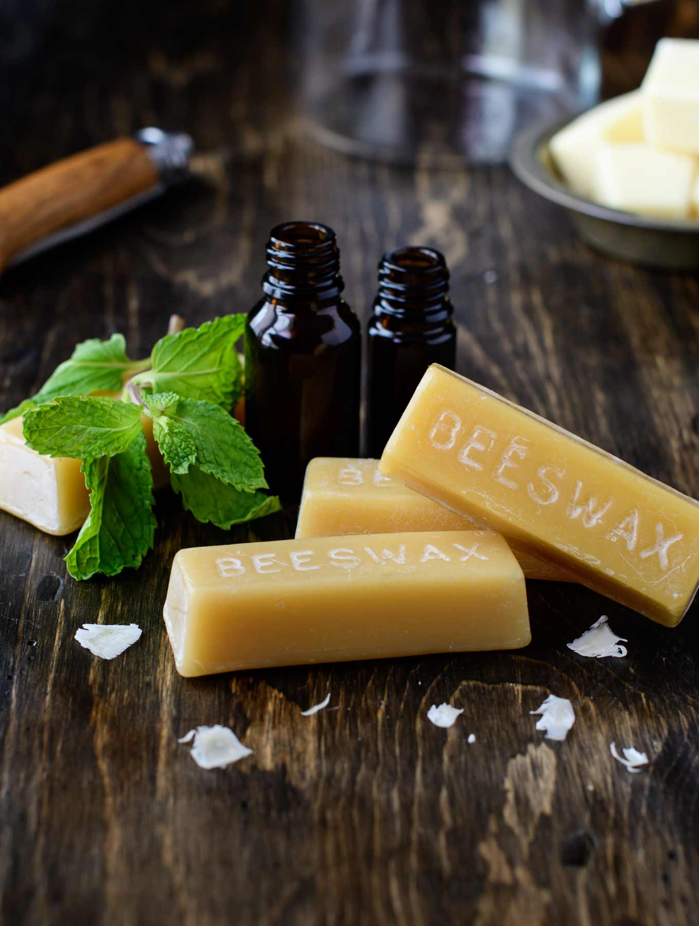 Beeswax and essential oil bottles on wood