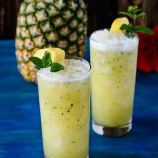 Two pineapple ginger faux-jitos on blue wood board