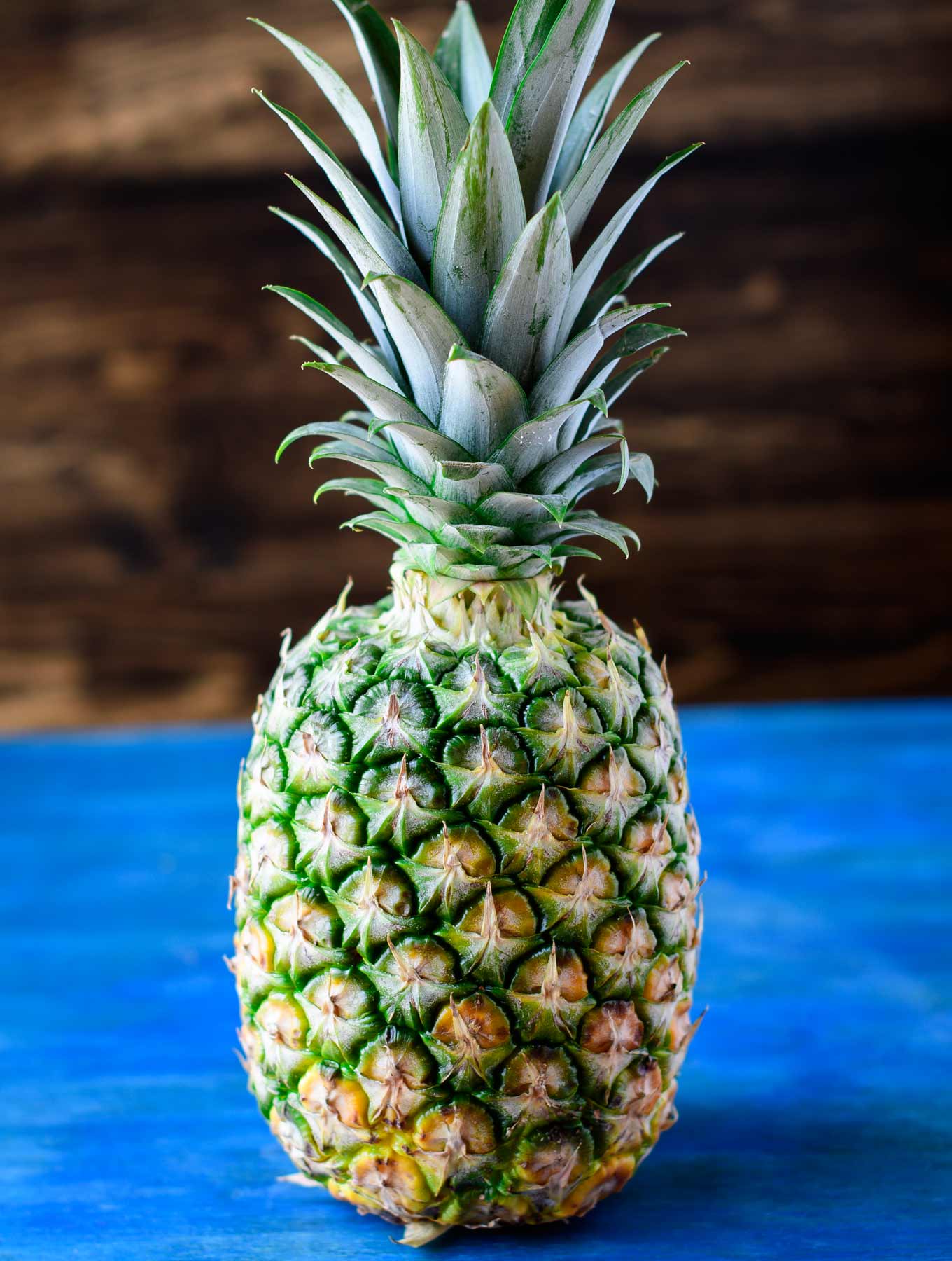 close up of pineapple on blue wood board