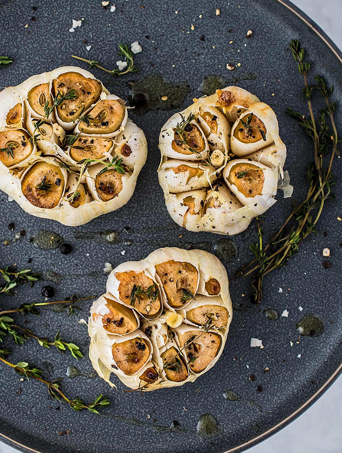 Three bulbs of roasted garlic on a plate