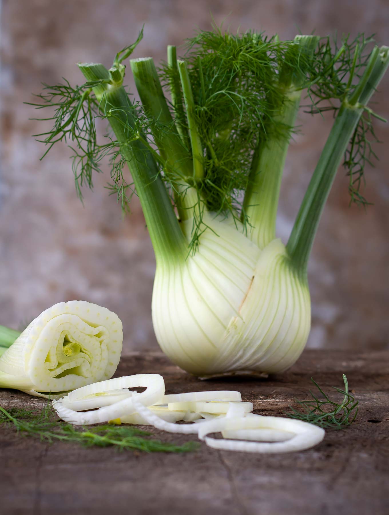 Fennel bulb with cut fennel on a wooden surface