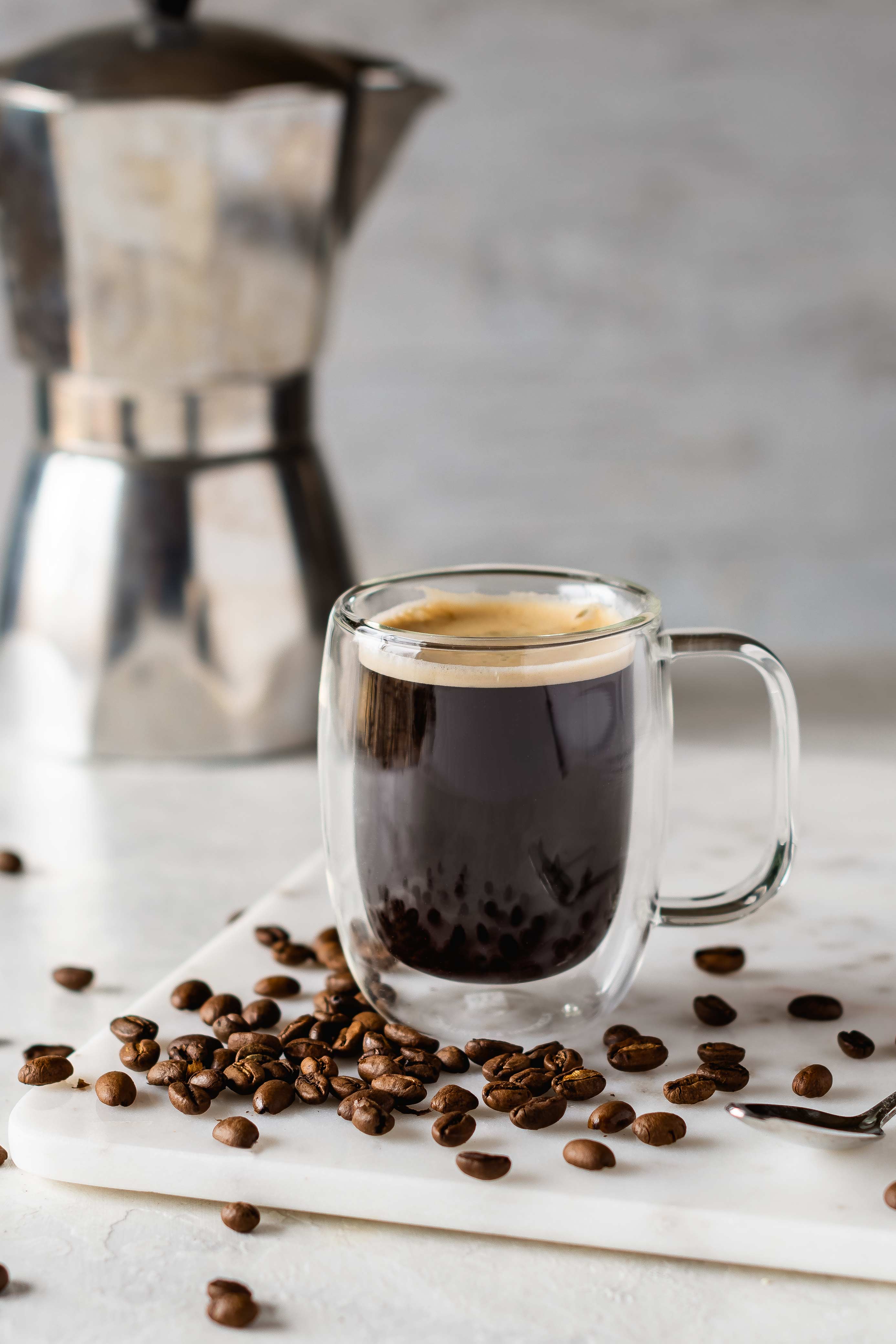 cup of espresso surrounded by coffee beans