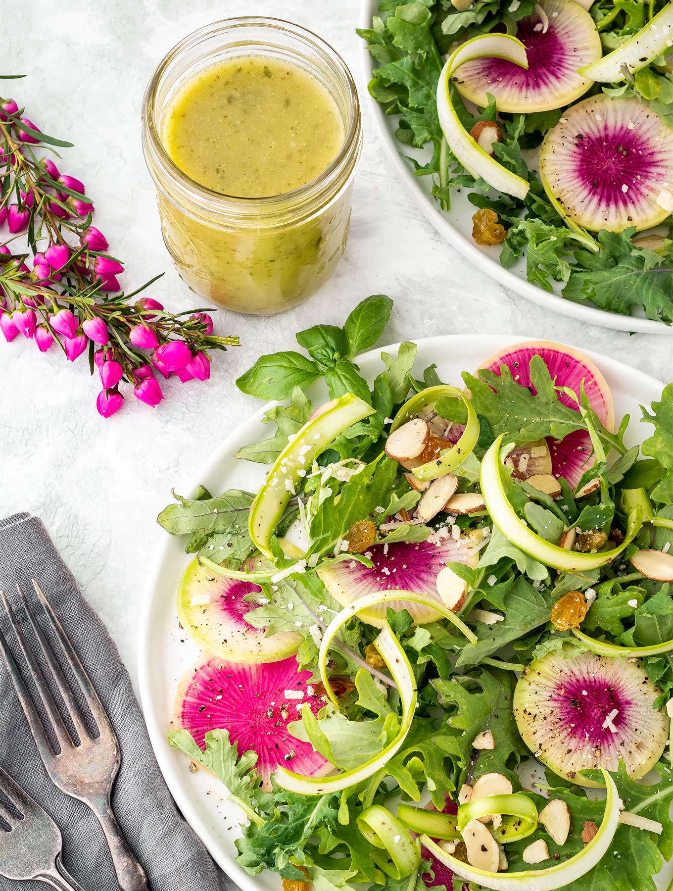 Two plates of shaved asparagus salad and watermelon radish with lemon basil dressing