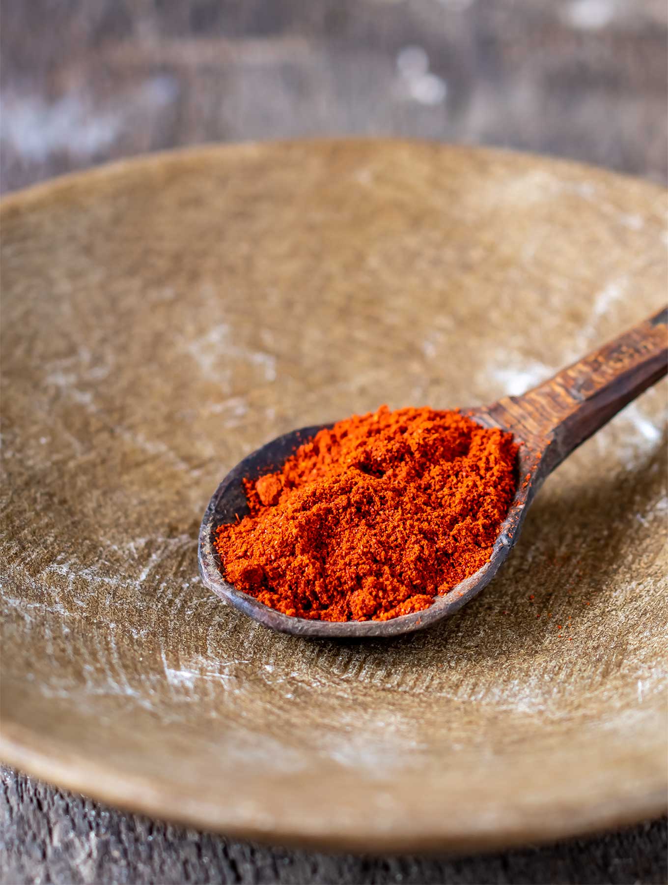 Spoon filled with smoked paprika in a bowl