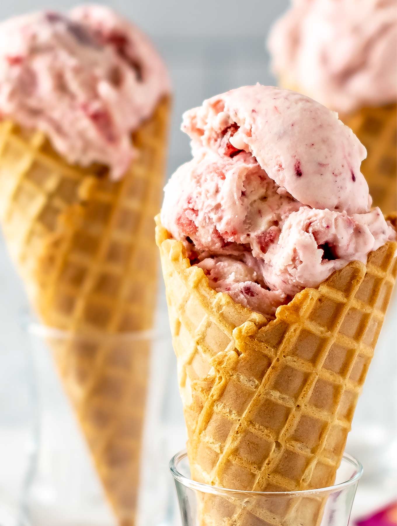 Close up of three cones of strawberry rose ice cream in glasses
