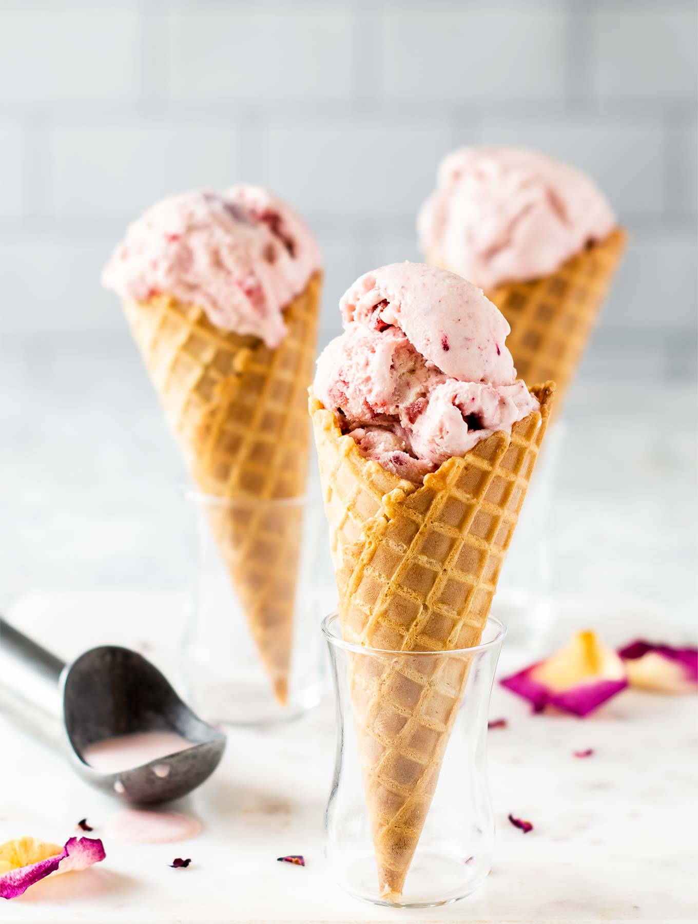 Three cones of strawberry rose ice cream in glasses