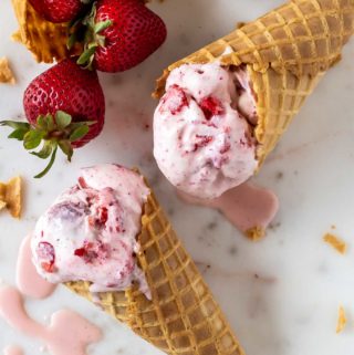 close up of two cones of strawberry rose ice cream on a marble surface