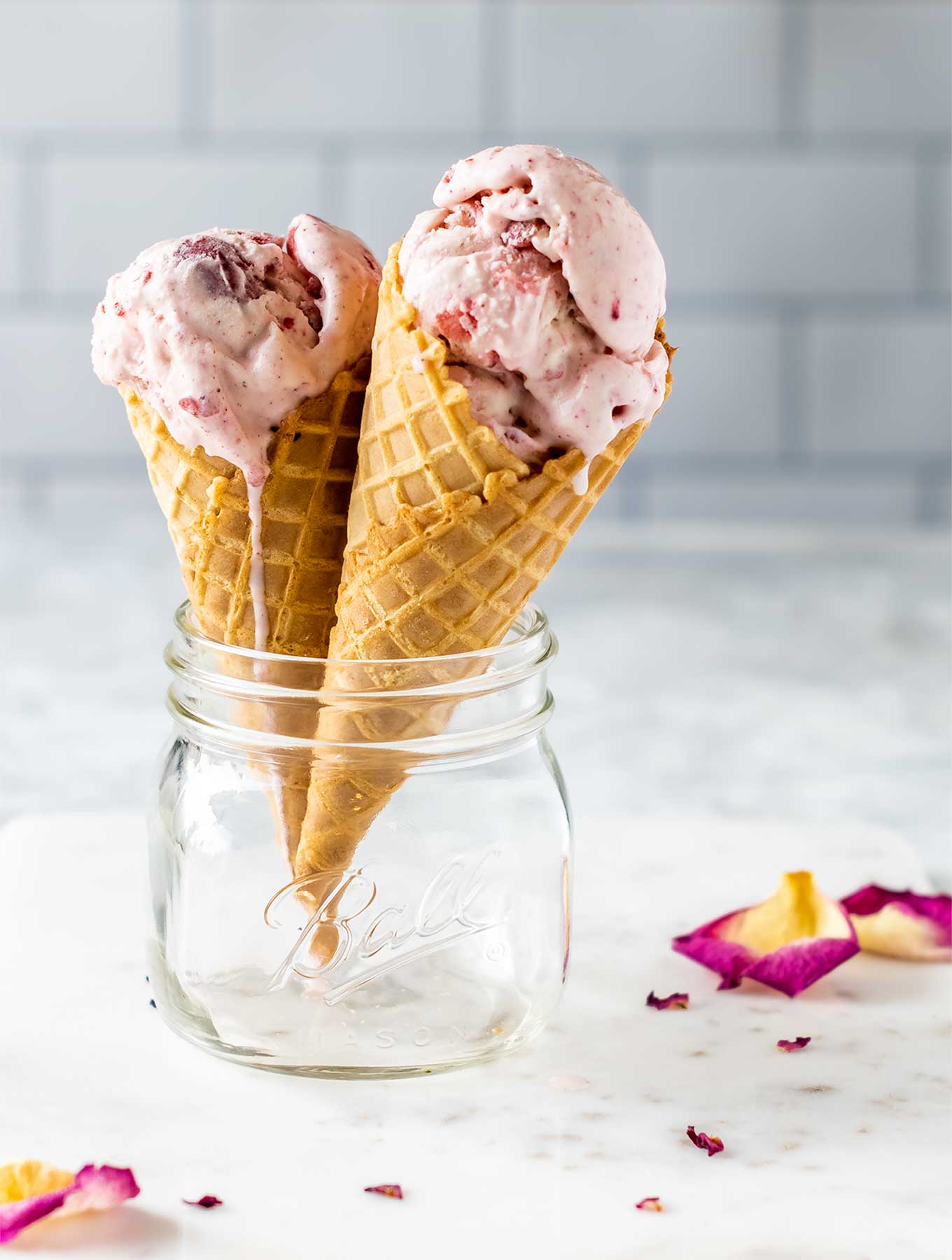 Two cones of strawberry rose ice cream in a jar
