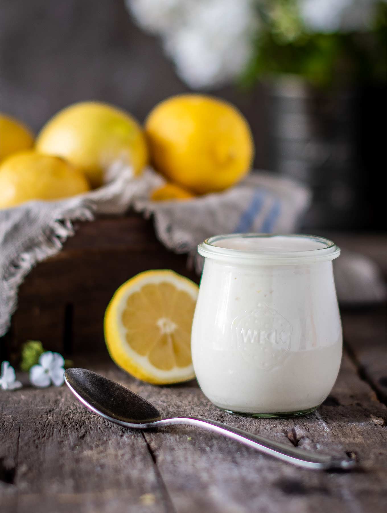 Jar of lemon aioli with fresh lemons on wood board