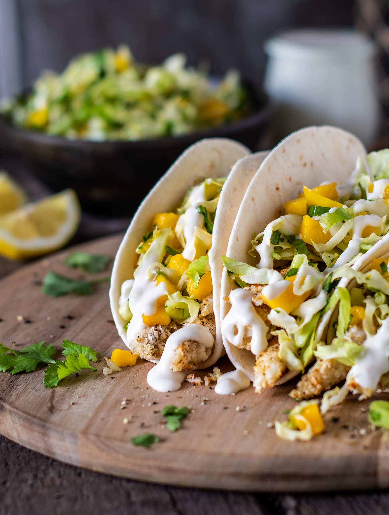 Three fish tacos with lemon aioli on a wood board