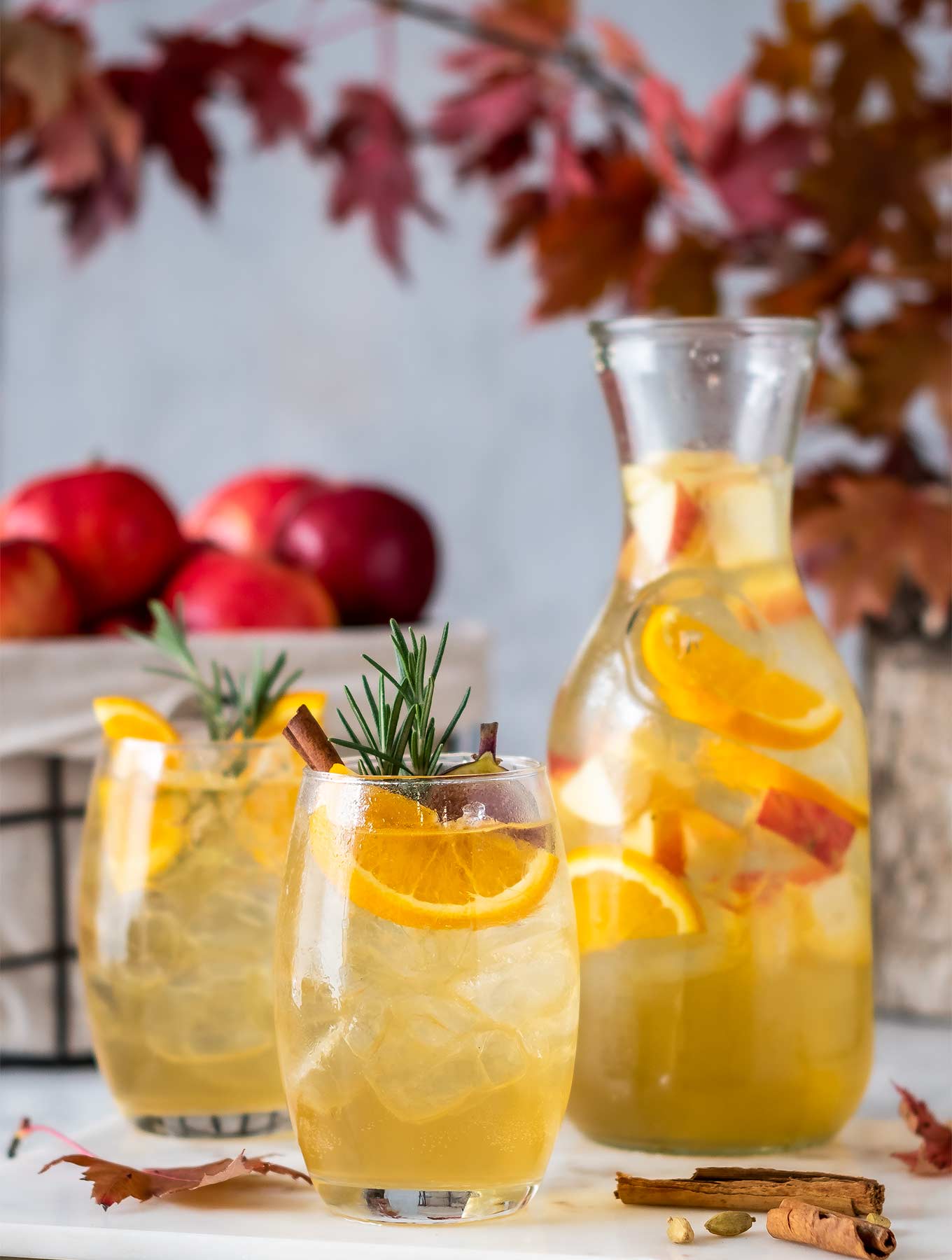 two glasses of fall sangria with a pitcher